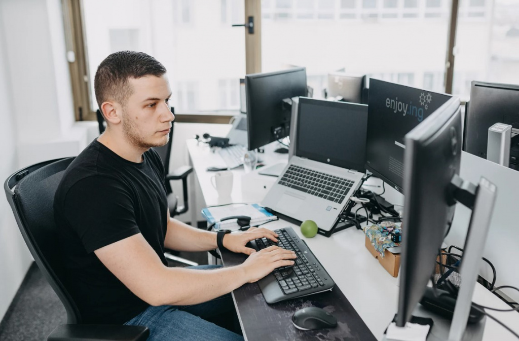 DevOps-инженер сидит за компьютером и ноутбуком